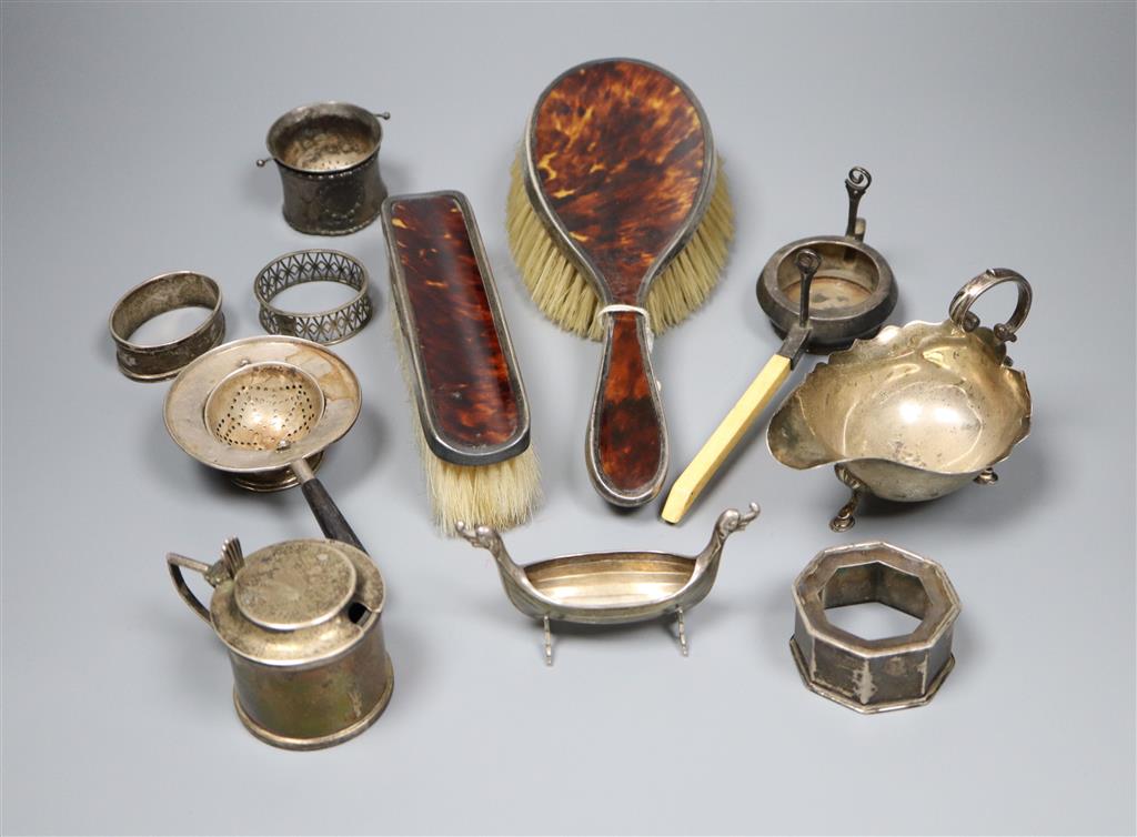 A silver mustard pot, silver sauceboat, three silver and one sterling napkin ring, two silver tea strainers etc.